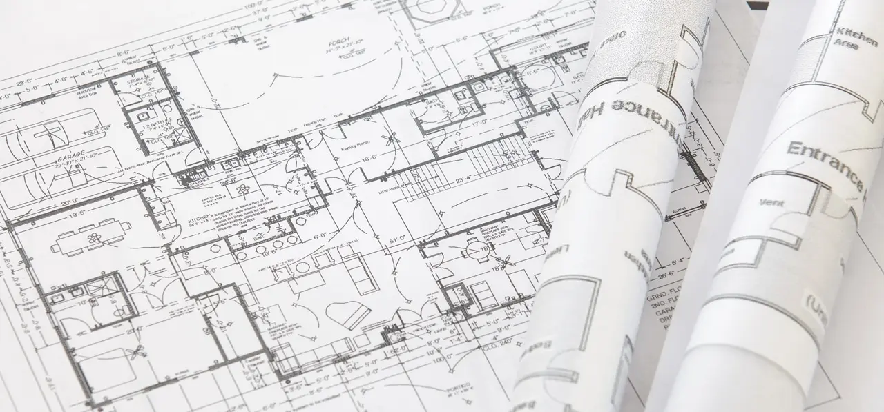 Architectural floor plans laid flat, with rolled drawings resting on top