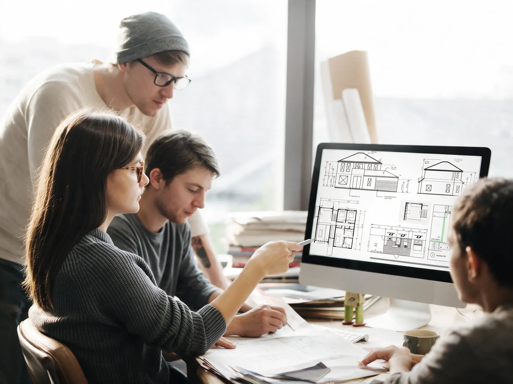 Design team reviewing exterior elevations and floor plans on screen during a drawing set coordination review