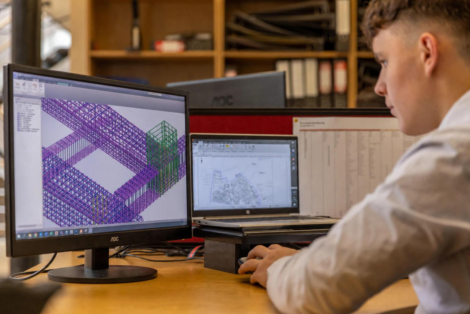 Structural engineer reviewing a beam-and-column reinforcement BIM model at an engineering workstation